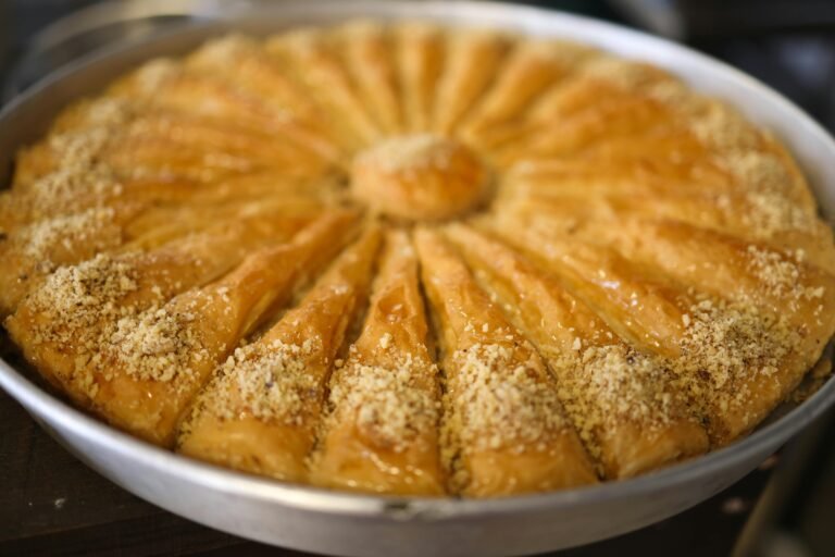 Delicious baklava with crusty layers and nuts, freshly baked in a round tray.